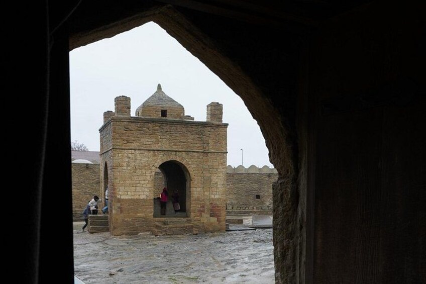A stone structure with a central archway, possibly a historical building or monument, viewed through an archway. 2