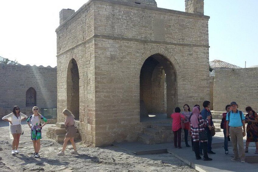 A group of people standing near an ancient stone structure with arched openings. 3