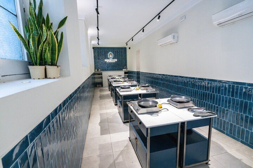 A kitchen with white countertops, blue tiled backsplash, and potted plants. 2