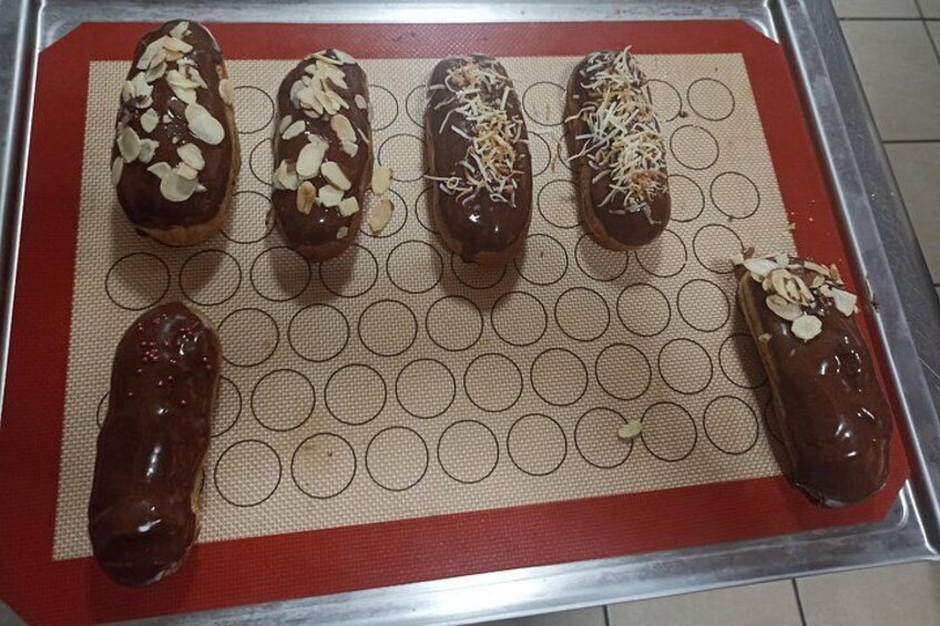 Five chocolate-covered pastries on a baking sheet. 3