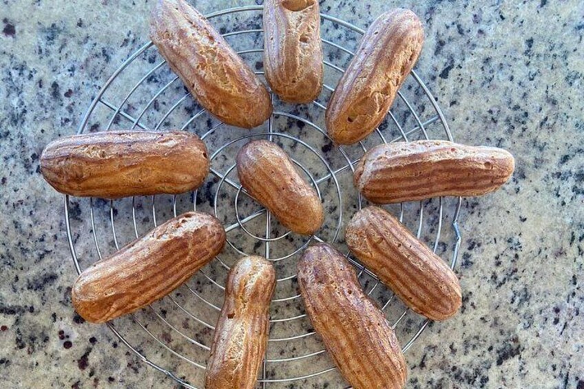 A wire cooling rack with several cylindrical pastries. 4
