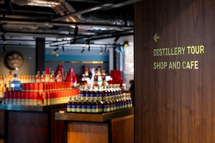 Ein Shop und Café für Distillery-Touren mit Regalen voller Flaschen und einer Holzwand mit Schrift. 2