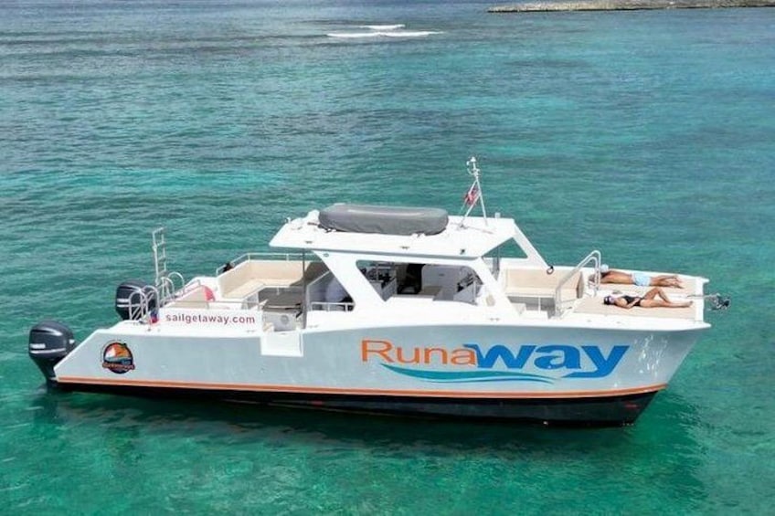 Un bateau appelé « Runaway » avec un site web, « sailgetaway.com », naviguant sur une mer turquoise. 2