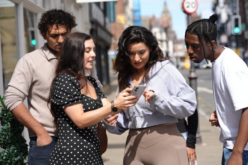 A group of people standing on a city street, one person holding a smartphone. 1