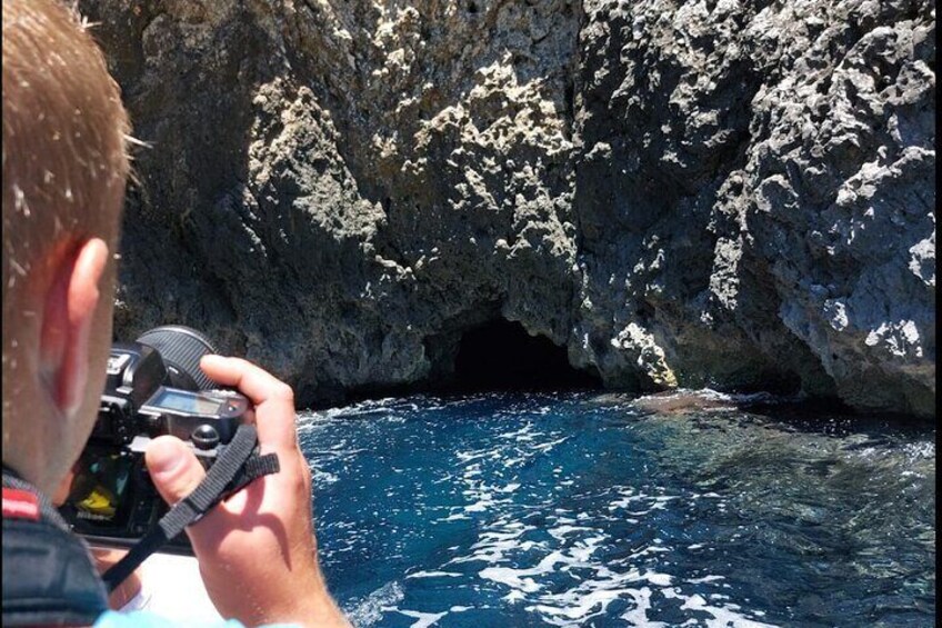 A person taking a photo of a rocky coastal area with clear blue water. 1