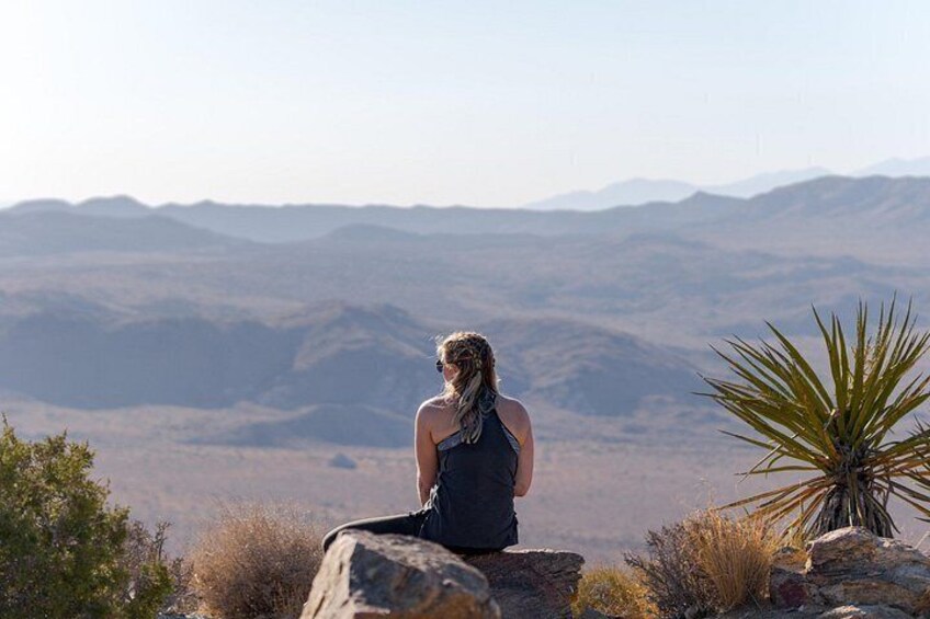 A person sitting on a rock with a mountainous landscape in the background. 1