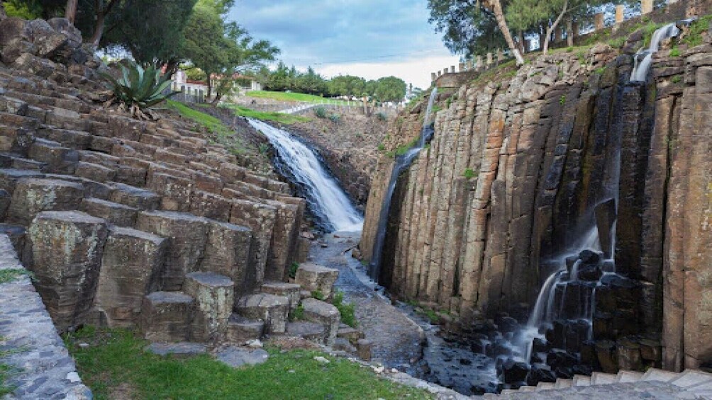 A stone cascade waterfall with steps leading down to a stream. 2