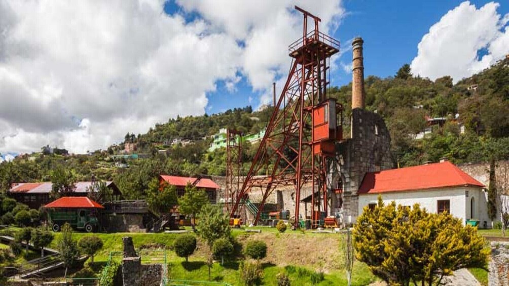 A mining operation with a large red tower and chimney, surrounded by residential buildings and greenery. 3