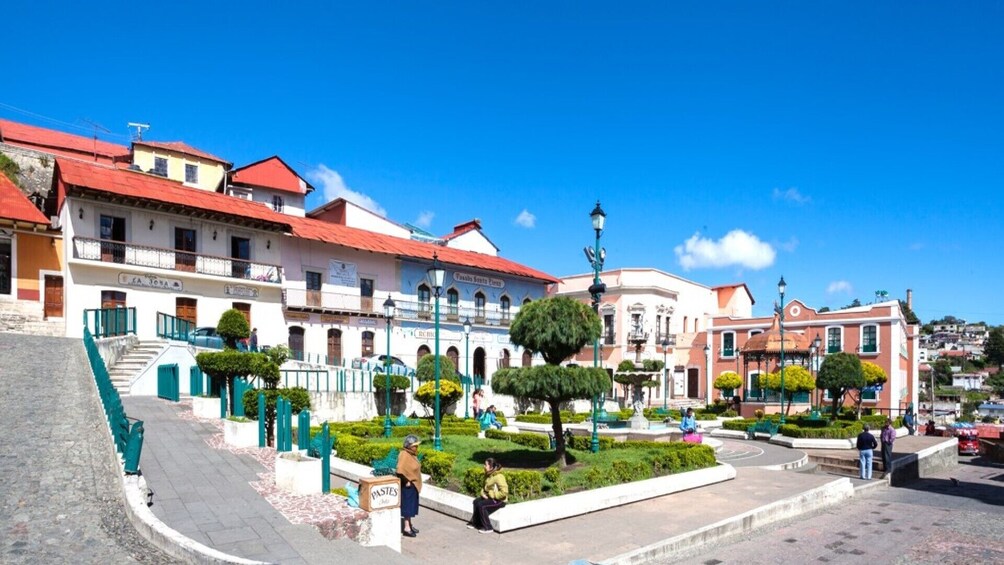 A town square with historic buildings, a fountain, and neatly trimmed trees. 4