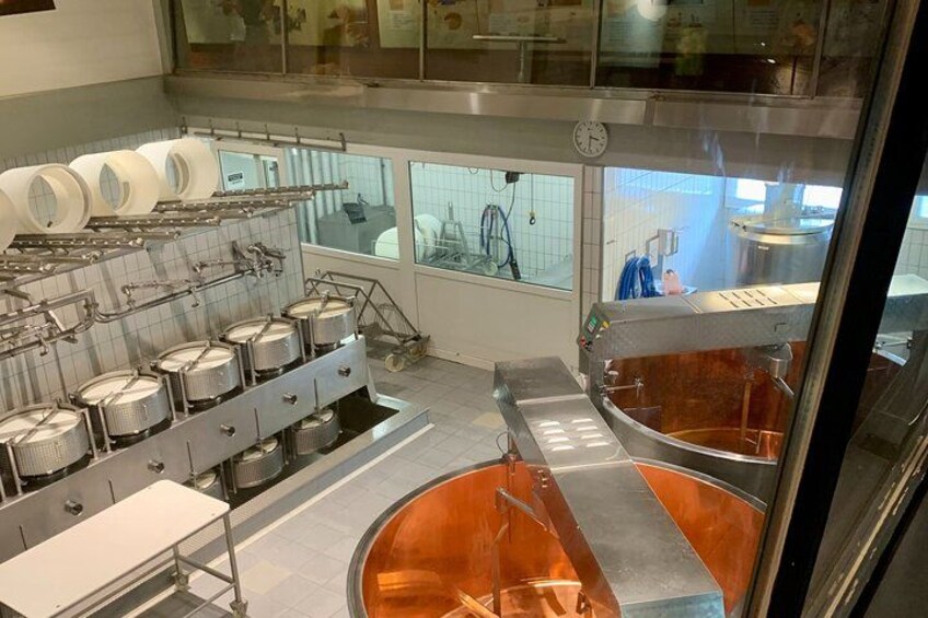 A commercial kitchen with stainless steel equipment, large copper pots, and a window overlooking the interior. 3