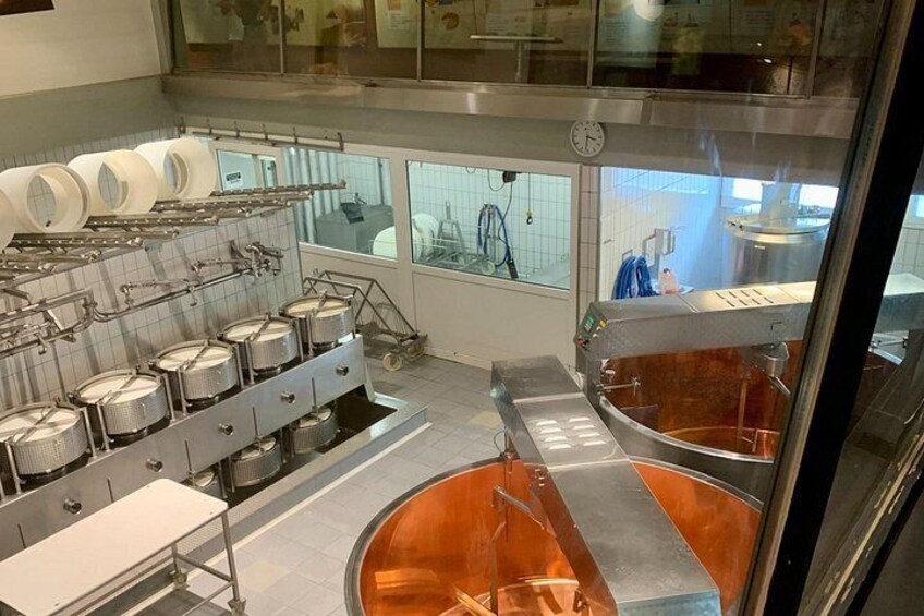 A commercial kitchen with stainless steel equipment, including pots, a large copper pot, and a conveyor belt system. 2