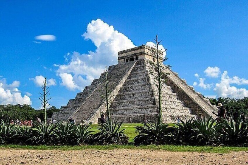 A large pyramid structure with a flat top, surrounded by greenery and a clear sky. 2