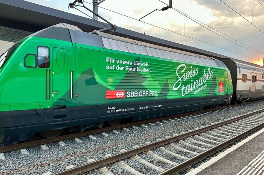 A green train with Swiss Tannwald logo and text on its side. 2