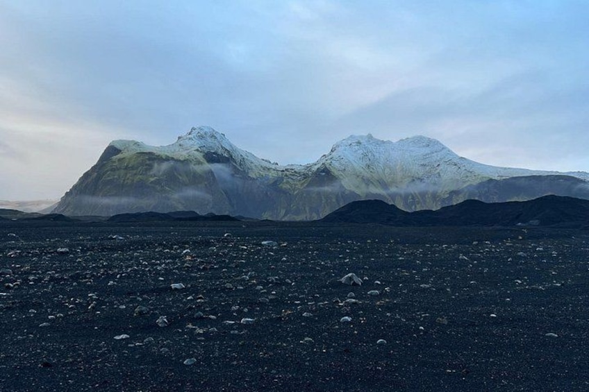 A volcanic landscape with a snow-capped mountain and a lava field. 5