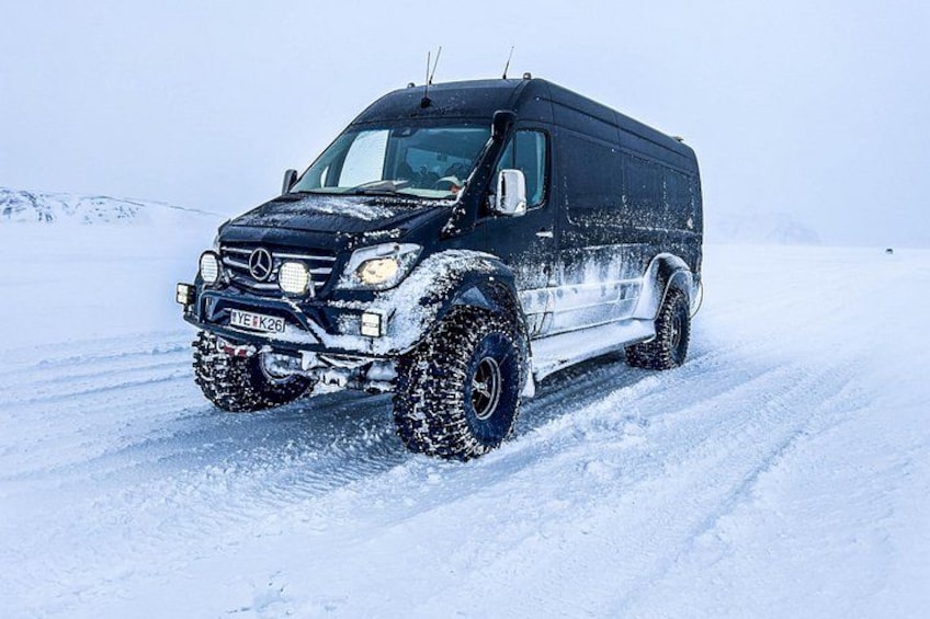 A black Mercedes-Benz G-Class SUV with off-road tires and a winch on a snowy landscape. 2
