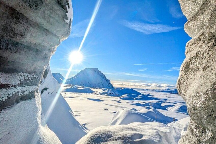 A snow-covered mountain landscape with a sun shining through a crevasse. 3