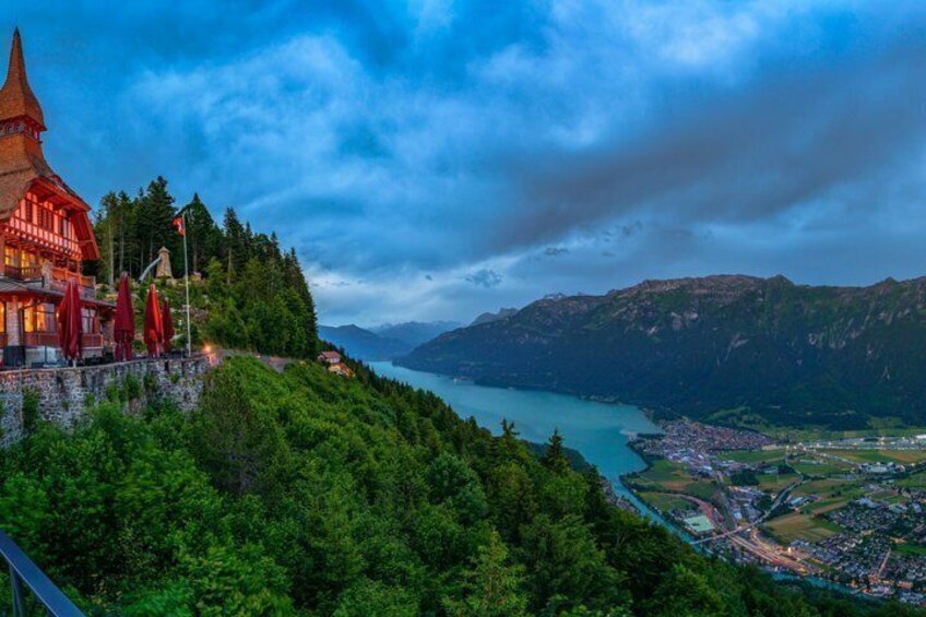 A mountain town with a church, a lake, and forested hills. 2