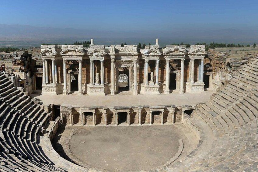 An ancient amphitheater with a central stage and tiered seating. 3