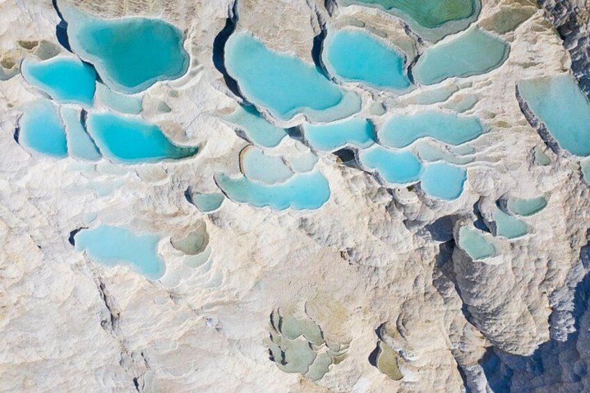 A landscape with terraced pools of turquoise water. 1