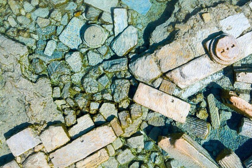 A mosaic of stone tiles with a circular metal object. 5
