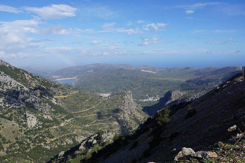 A mountainous landscape with a valley, a lake, and a clear sky. 1