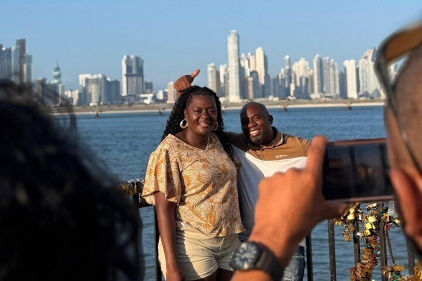 A city skyline with high-rise buildings, a body of water, and a person taking a photo. 1
