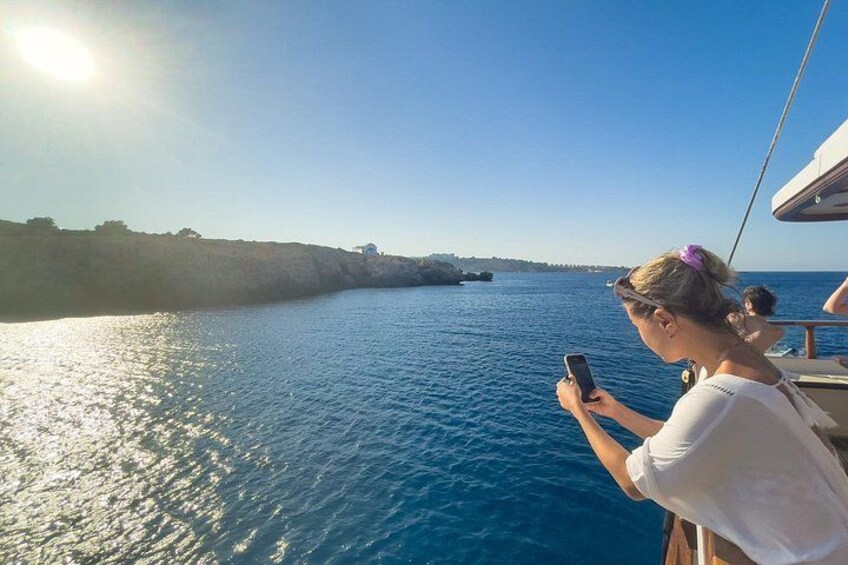 A person on a boat, looking at a smartphone, with a clear sky and calm sea. 5