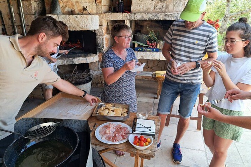 People cooking outdoors with a stone oven and a grill. 4