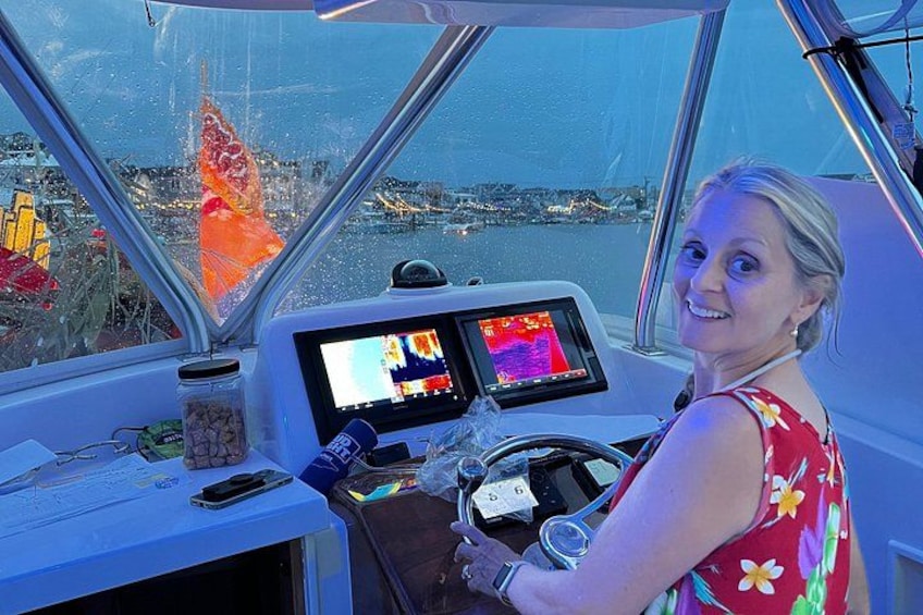 A person steering a boat with two screens displaying navigation information. 4