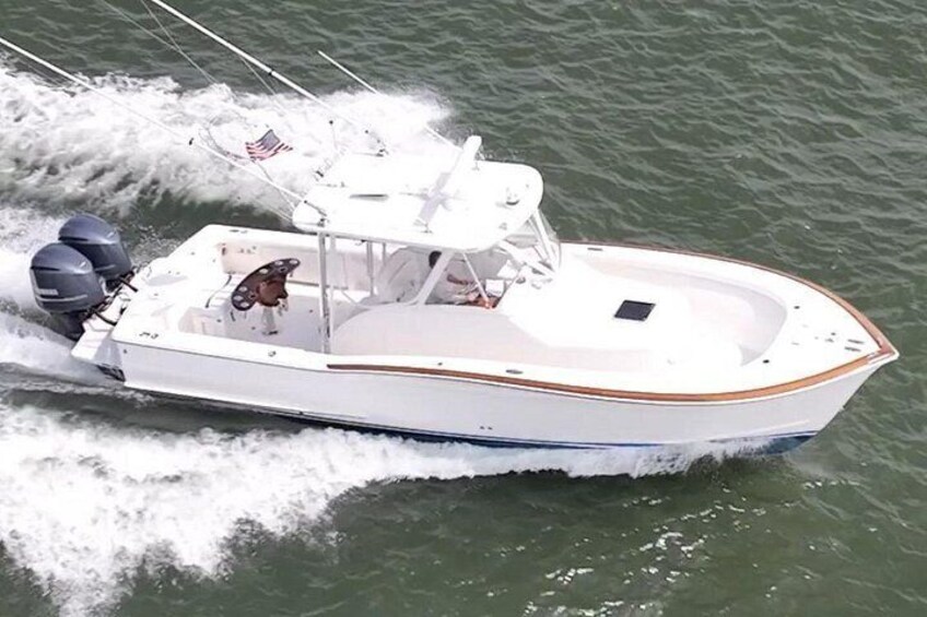 A white motorboat with a blue stripe, American flags, and a wake behind it. 1