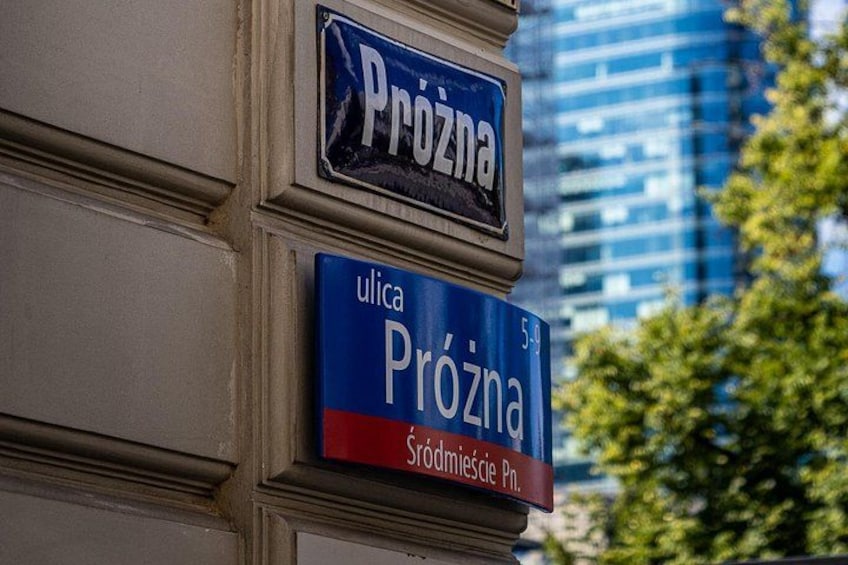 Señal de calle con el nombre 'Prozna' y 'ulica Prozna', con un edificio al fondo. 2