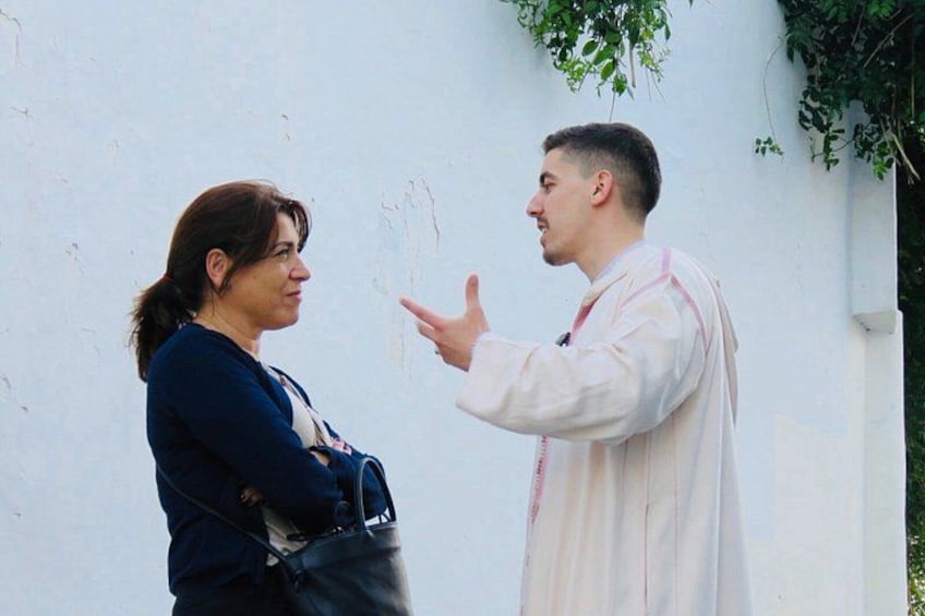Zwei Personen vor einer weißen Wand, eine Person gestikuliert mit der Hand. 3