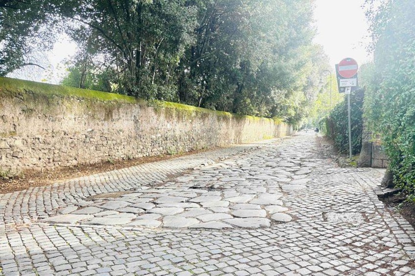 Una calle adoquinada con un muro de piedra a un lado y una señal de prohibido el paso al otro. 2