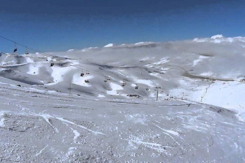 Een besneeuwde helling met skiliften en skipistes. 4