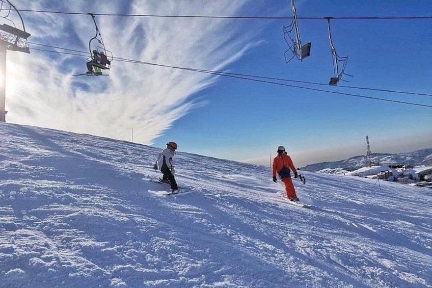Een besneeuwde piste met een skigebied en skiërs. 2