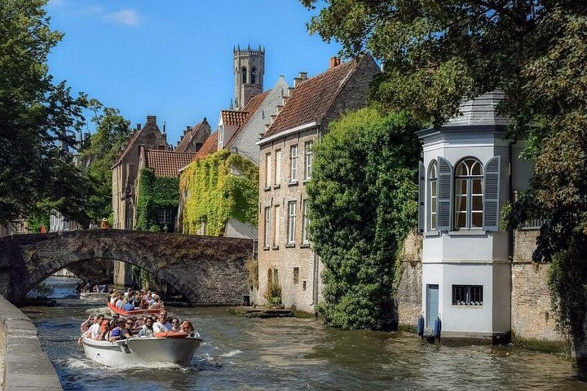A boat with passengers on a river, a stone bridge, and historic buildings with a tower. 4