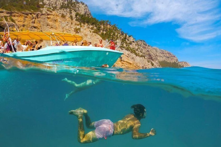 A person swimming underwater near a boat with people on a nearby boat. 4