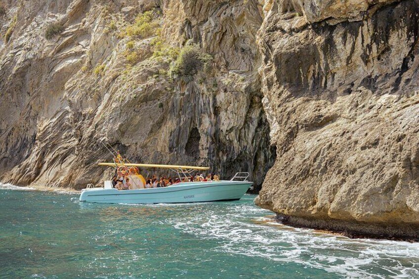 A boat with passengers near rocky cliffs. 5