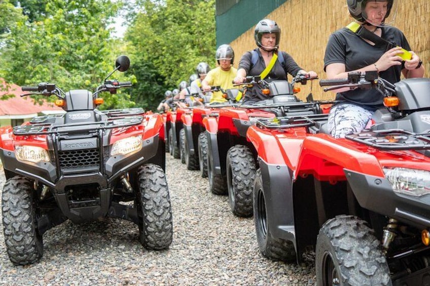A line of red ATVs parked on gravel. 2