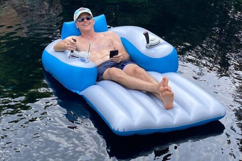 Una persona recostada sobre una balsa hinchable azul y blanca en el agua. 1