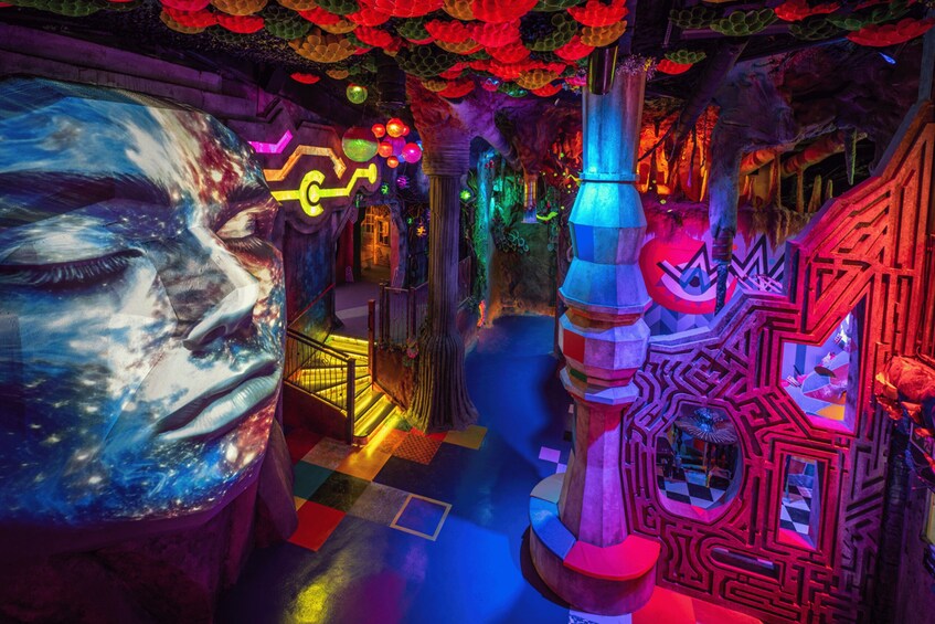A colorful, illuminated indoor space with a large mural, geometric structures, and a checkered floor. 2