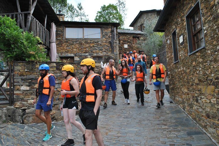 A group of people in orange vests walking down a stone-paved street in a village. 3