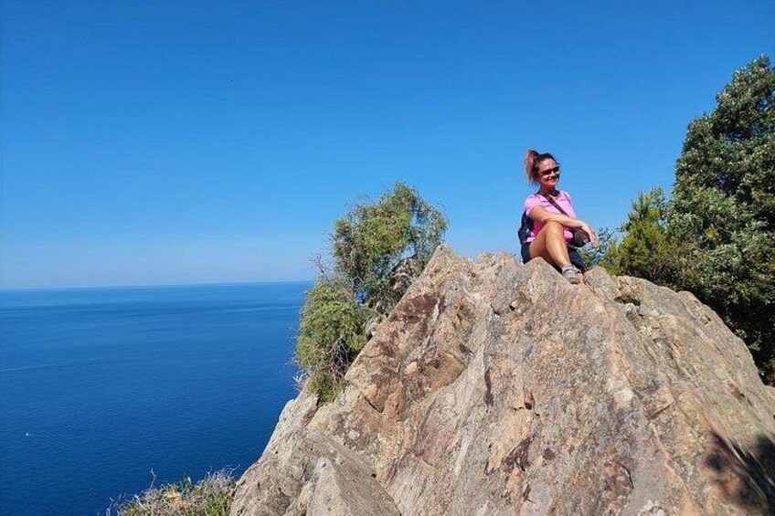 Eine Person sitzt an einem großen Felsen am Meer. 1