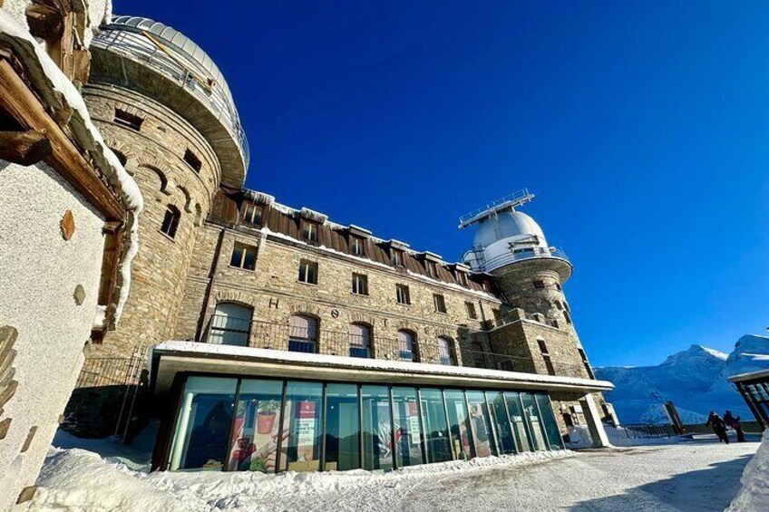 A historic building with a dome and a glass entrance, surrounded by snow. 1