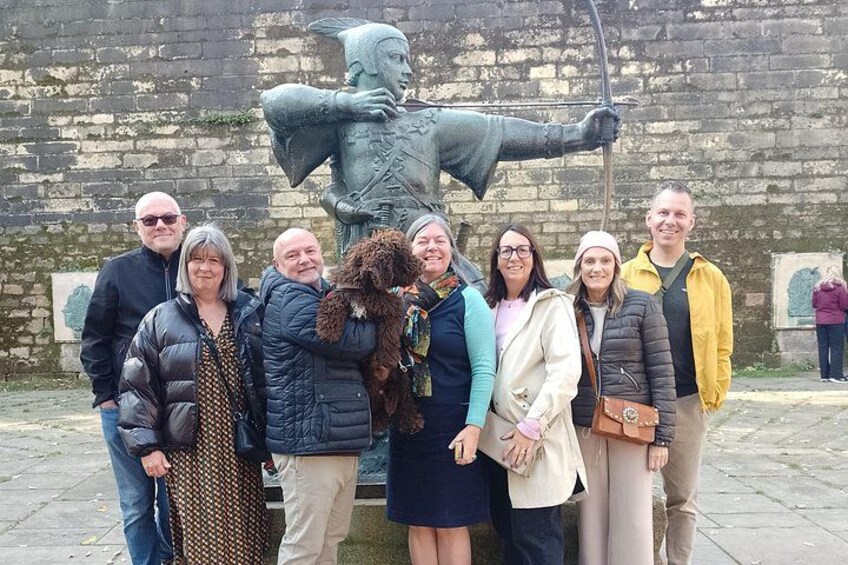 A group of people posing in front of a historical statue. 2