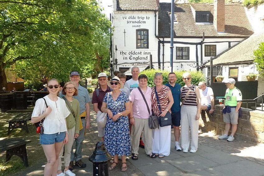 A group of people posing in front of a building with a sign that reads 'the oldest inn in England.' 1