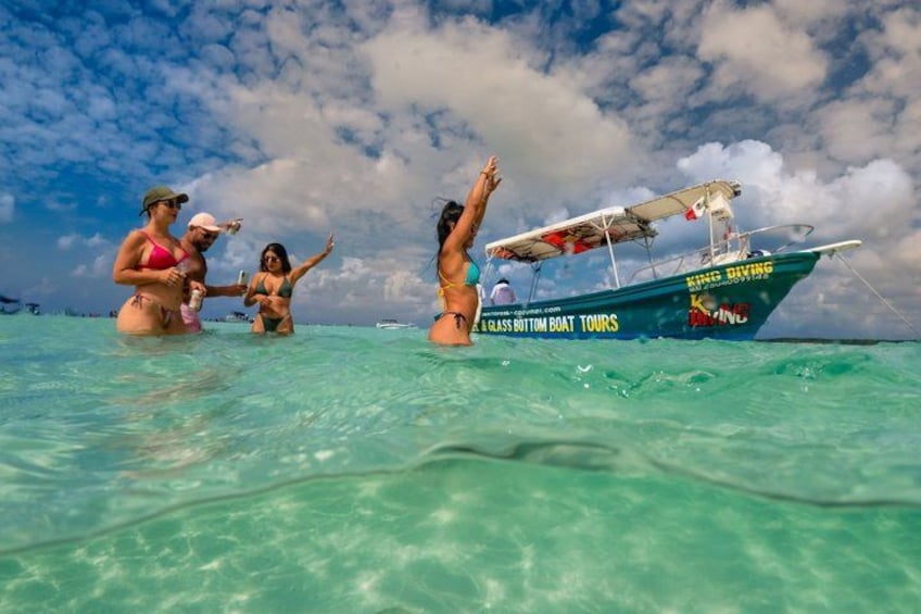 Menschen im Meer mit einem Boot, auf dem 'King Diving' und 'Glass Bottom Boat Tours' steht. 5