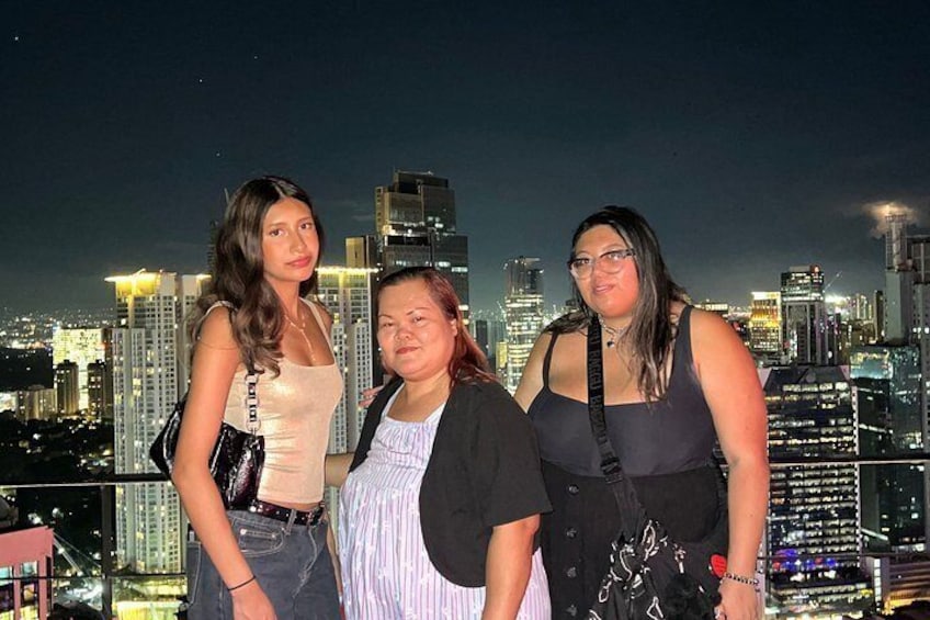 Three individuals posing with a city skyline in the background. 4