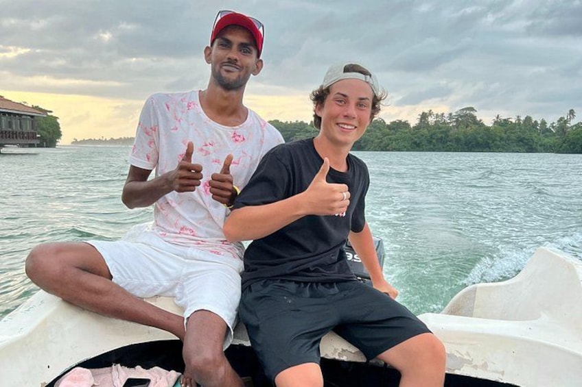 Two people on a boat with a body of water and a distant shoreline in the background. 1