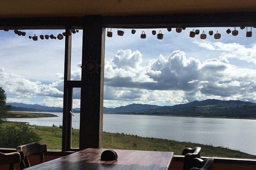 Una mesa con sillas orientada a un amplio ventanal con vistas a un lago y montañas. 2